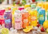 Colorful hard seltzer cans with fruits and ice.