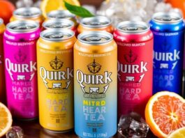 Colorful cans of Quirk Hard Tea with citrus fruits.